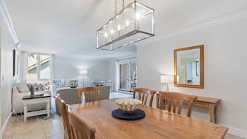 Comedor con mesa de madera, sillas y un cuenco decorativo en el centro. Una lámpara colgante ilumina la mesa.