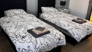 A double bed with a floral bedspread and a folded towel on the side. - Modern 2-bed house  in Blyth centre  with two bedrooms and two bathrooms (Blyth)