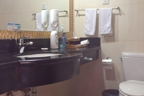 Un baño con un lavabo negro, inodoro blanco y toallas colgadas en un perchero.