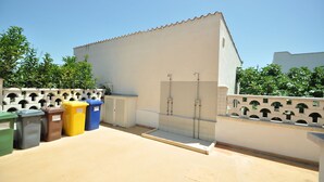 Una terrazza sul tetto con doccia a vetri, cestini per rifiuti all'aperto e un muro bianco con archi decorativi.