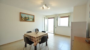 Un'area pranzo con un tavolo apparecchiato per due persone, un quadro appeso al muro e un frigorifero nell'angolo.
