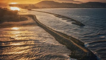 Un río con una orilla rocosa y un paisaje urbano distante al atardecer.