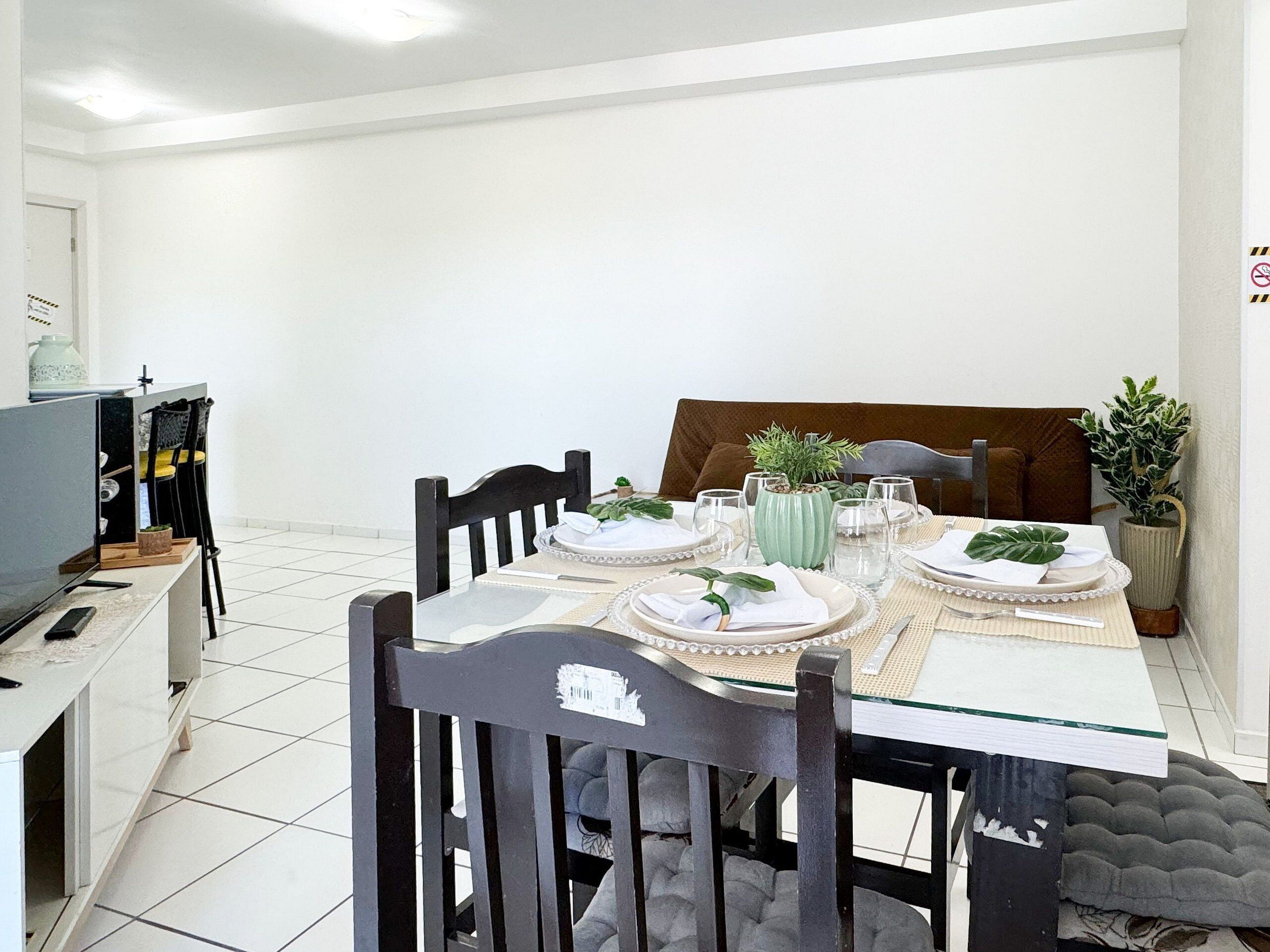 Comedor con una mesa de vidrio dispuesta para cuatro personas, rodeado de sillas de madera.