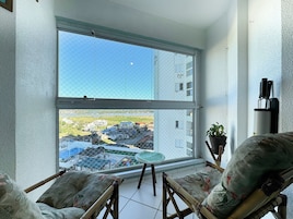 Uma varanda com vista para uma área residencial, um vaso de planta e uma cadeira.
