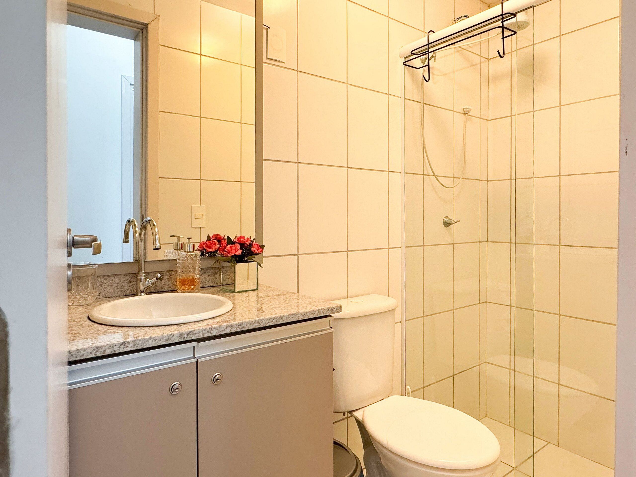 A bathroom with a sink, mirror, toilet, and shower.