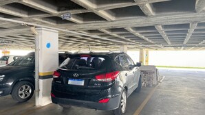 Eine Parkgarage mit einem schwarzen SUV, geparkt in der Nähe einer Säule, einer Betondecke und einem Schild mit der Aufschrift '706-B BOX 069'.