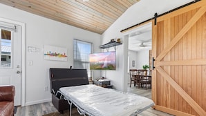 A modern room with a bed, a TV, a wooden door, and a dining area.