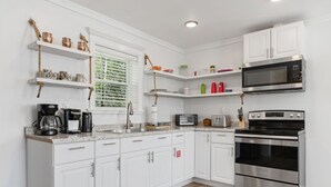 A modern kitchen with white cabinetry, stainless steel appliances, and a wooden countertop.