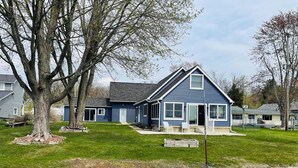 A residential house with a front yard, a dock, and a small pond. - Comfortable 3-bedroom lake house with AC, WiFi on Devils Lake in Addison, MI. (Addison)