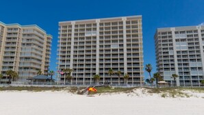 A beachfront hotel with multiple high-rise buildings, a sandy beach, and palm trees. - Windward Pointe 104 with Beach Access (Orange Beach)