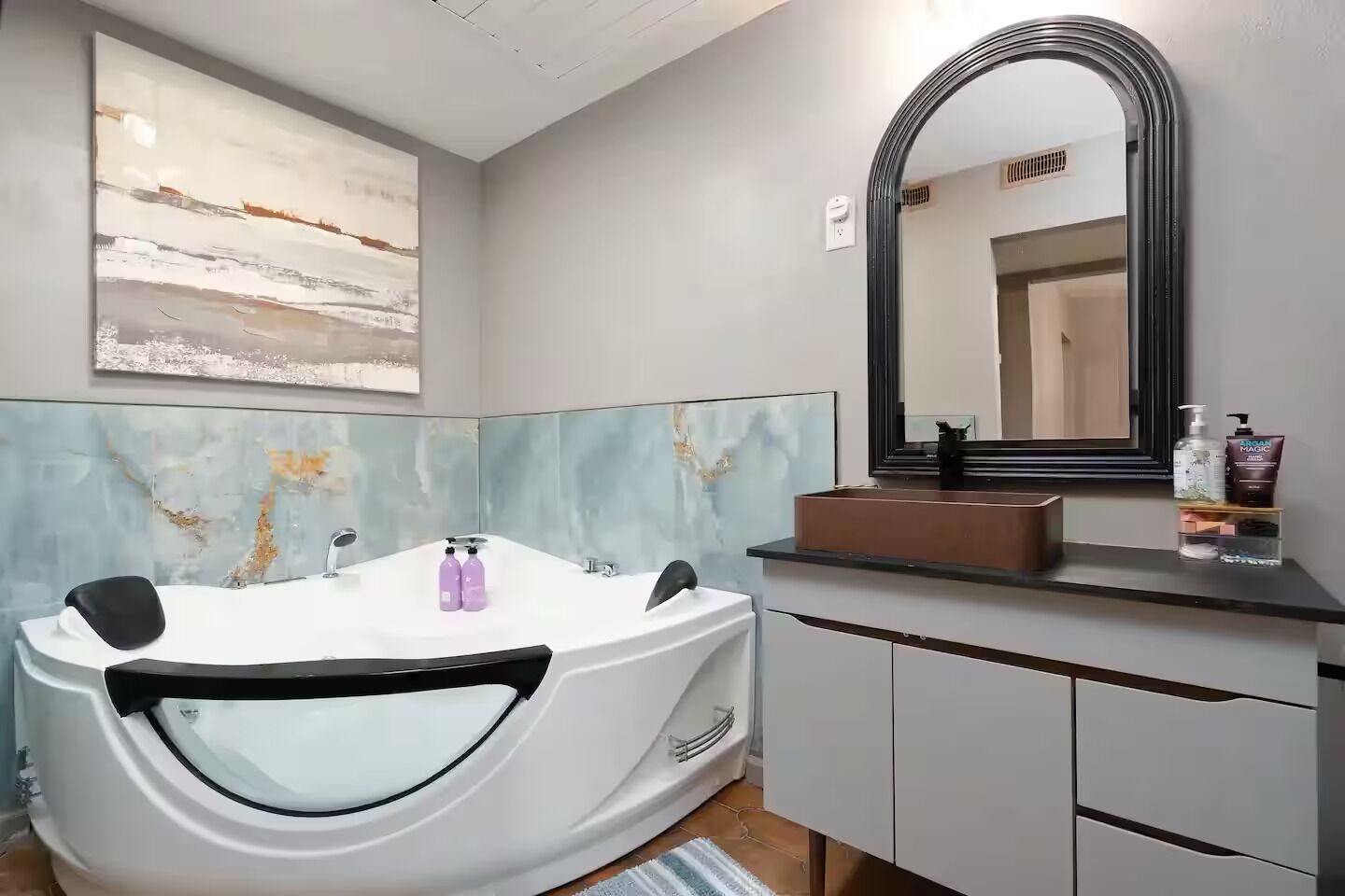 A modern bathroom with a freestanding bathtub, a large mirror, and a vanity with a sink.
