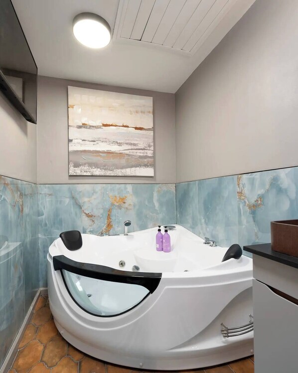 A modern bathroom with a freestanding bathtub, a large abstract painting on the wall, and a marble backsplash.