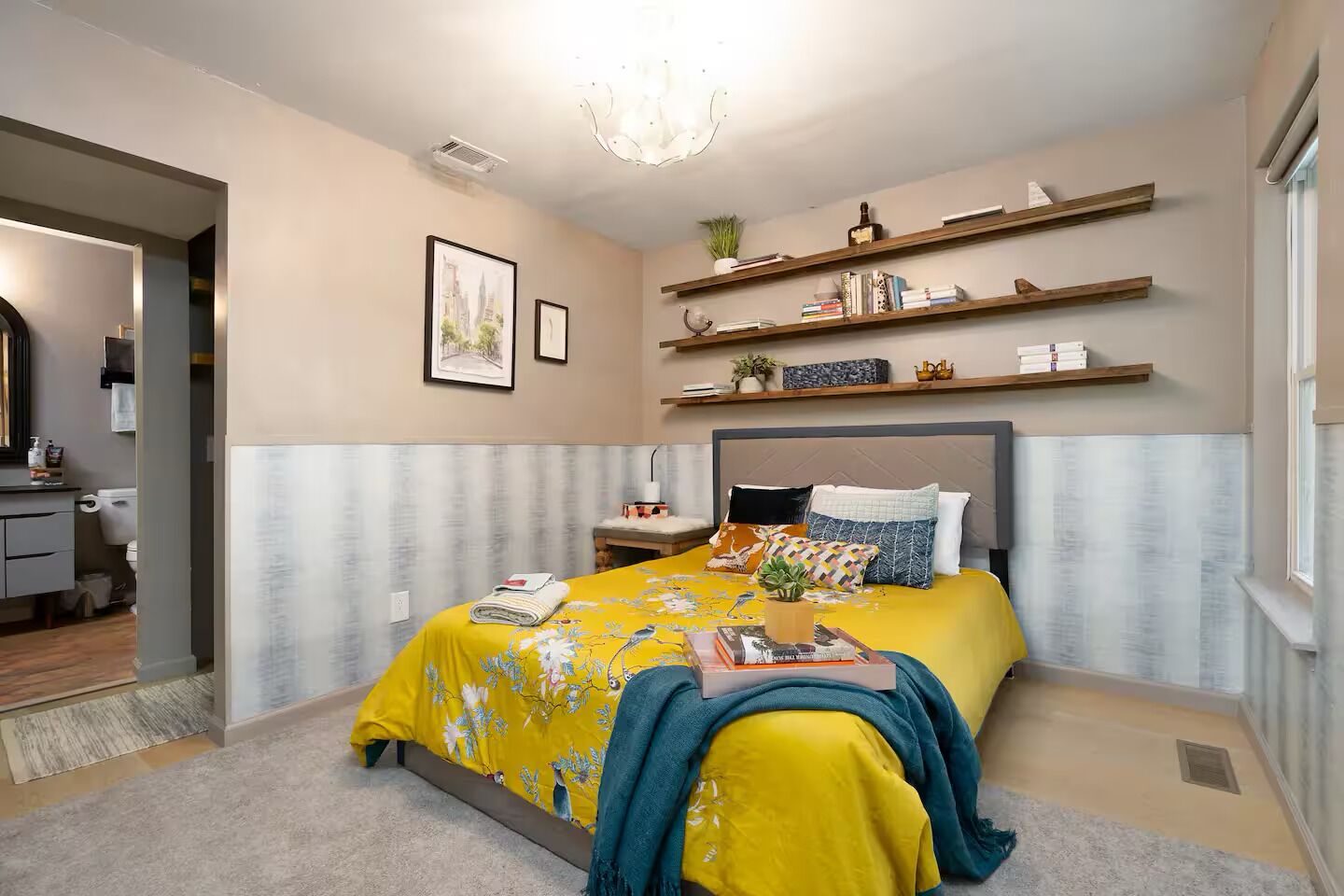 A bedroom with a bed, bedside tables, a mirror, and a window.
