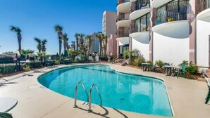 Une piscine à bordures courbes, entourée d’une clôture et de palmiers.