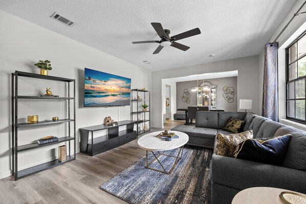 A modern living room with a grey sofa, a round coffee table, and a bookshelf.