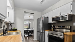 Una cocina moderna con electrodomésticos de acero inoxidable, encimera de madera y armarios blancos.