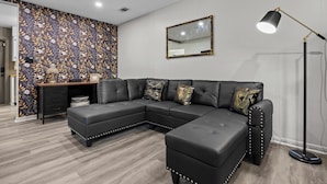 Una sala moderna con un sofá modular, un escritorio y una lámpara de pie.