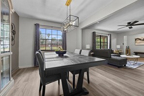 A spacious living area with a dining table, sofa, and a ceiling fan.