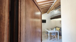 An open wooden door leading into a room with a dining table, chairs, and a staircase.