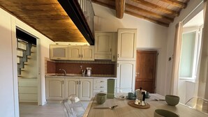 A modern kitchen with white cabinets, a wooden ceiling, and a dining area with a table set for two.