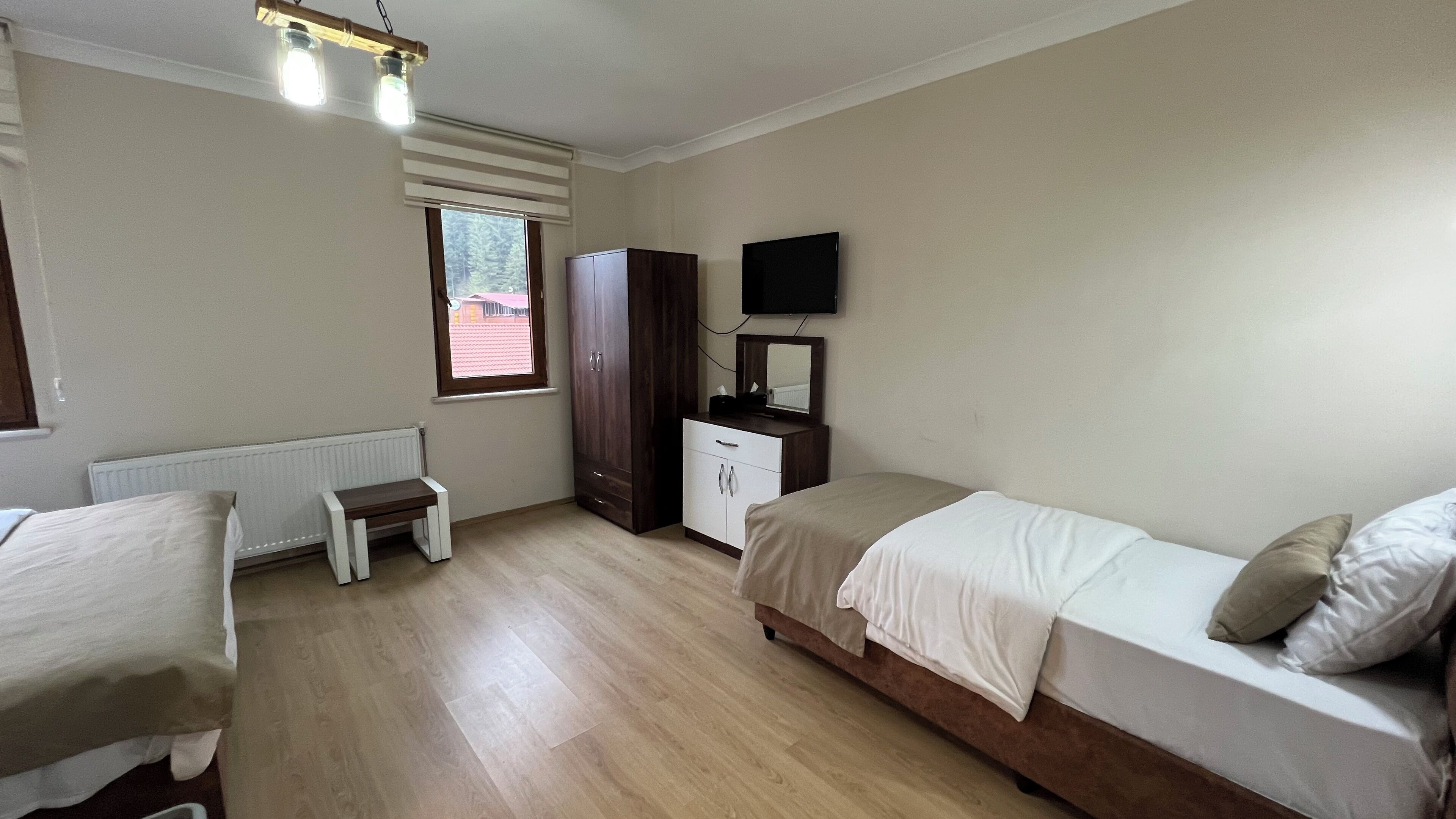 Un dormitorio con cama, una mesita, armario, televisor y ventana.