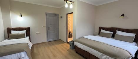Habitación de hotel con dos camas, piso de madera, una puerta y un basurero.