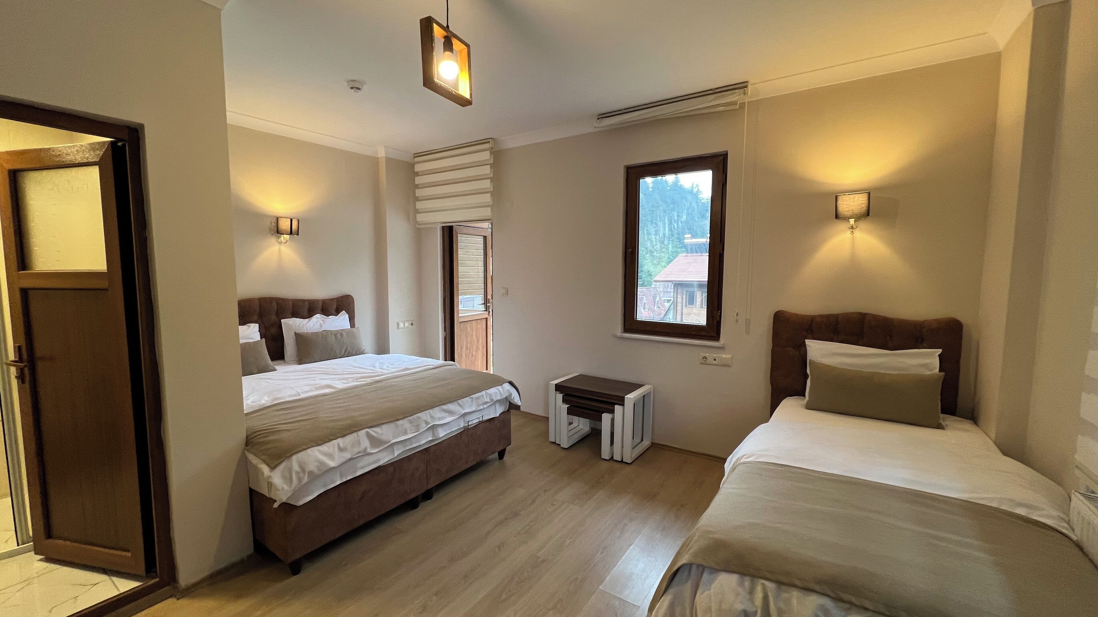 Una habitación de hotel con dos camas, una mesita y una ventana que ofrece vistas a edificios.