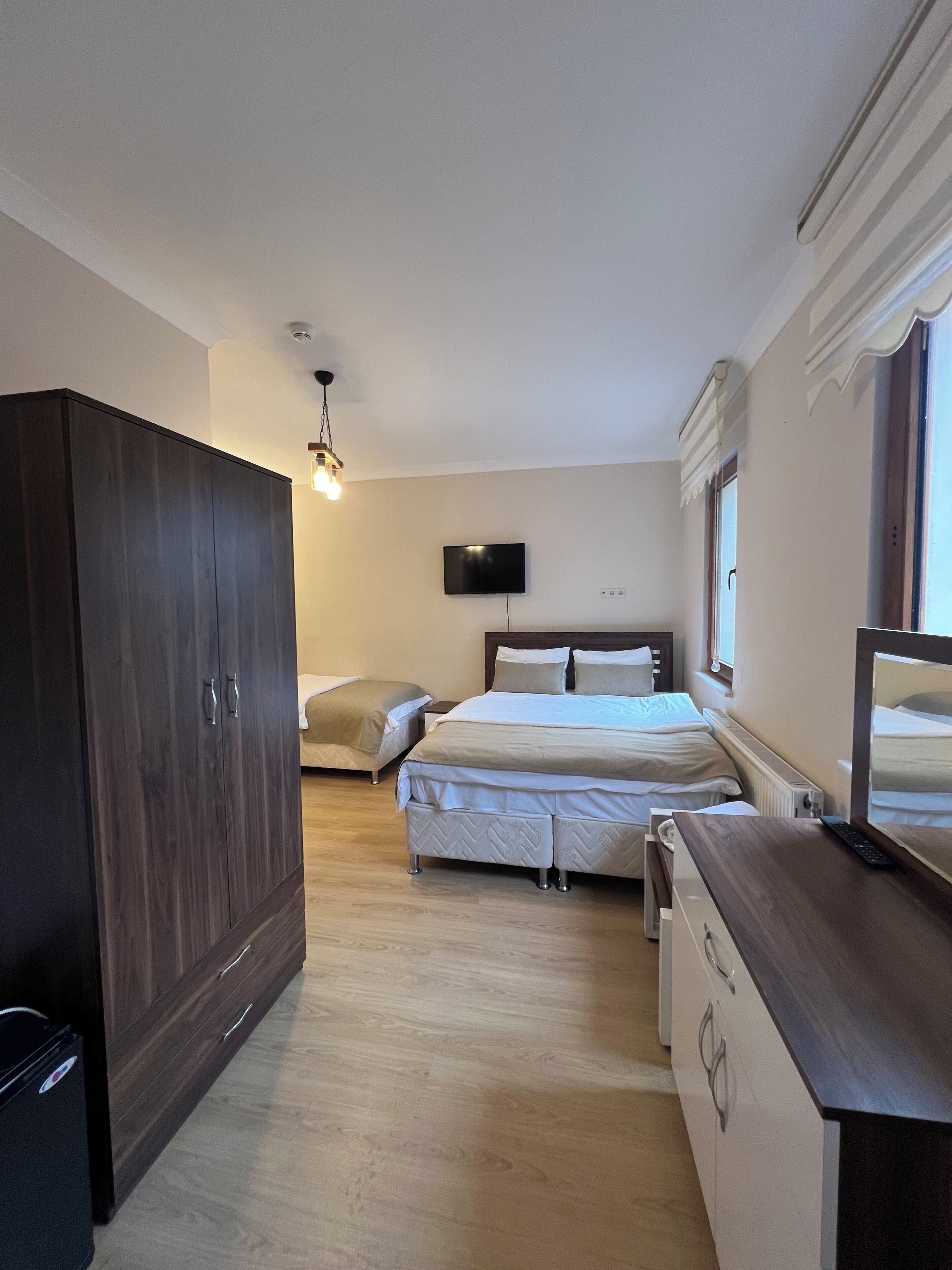 A bedroom with a bed, a wardrobe, a desk, and a television.