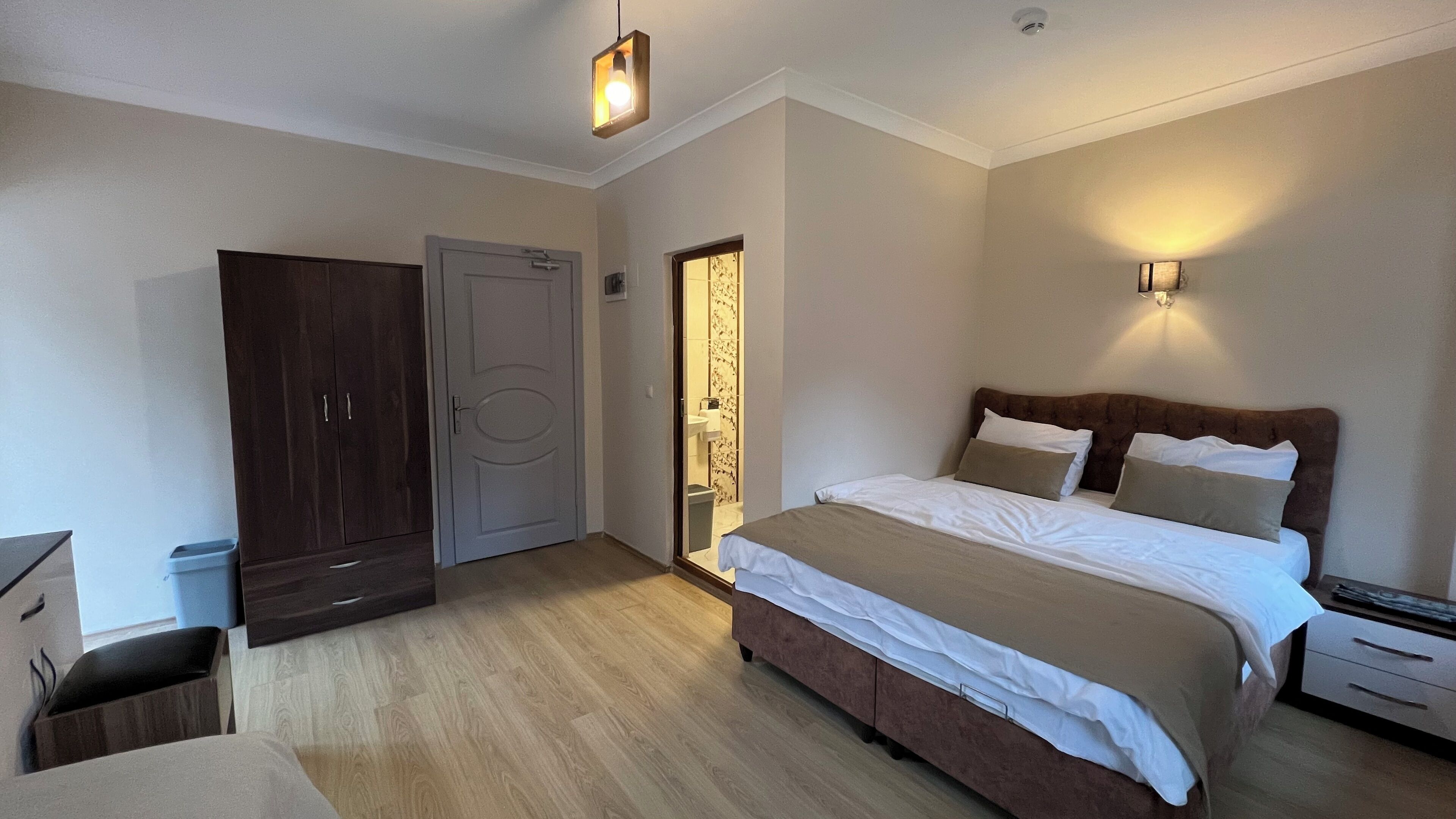 A bedroom with a bed, bedside tables, a wardrobe, and a bathroom door.