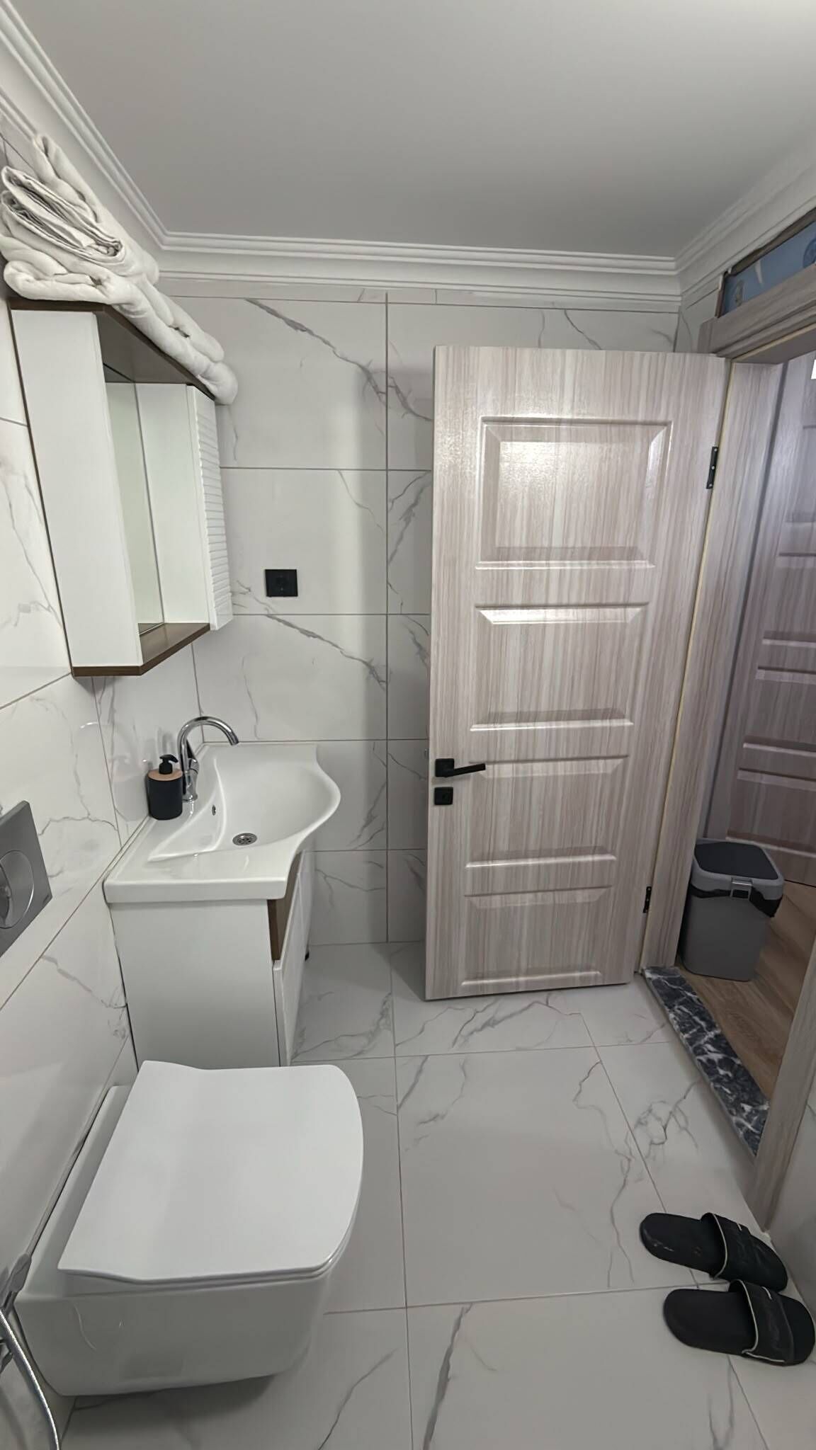 Ein Badezimmer mit weißem Waschbecken, Toilette und einem Spiegel darüber.