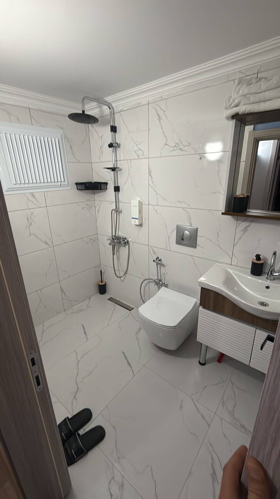 Baño con ducha, inodoro, lavabo y espejo.