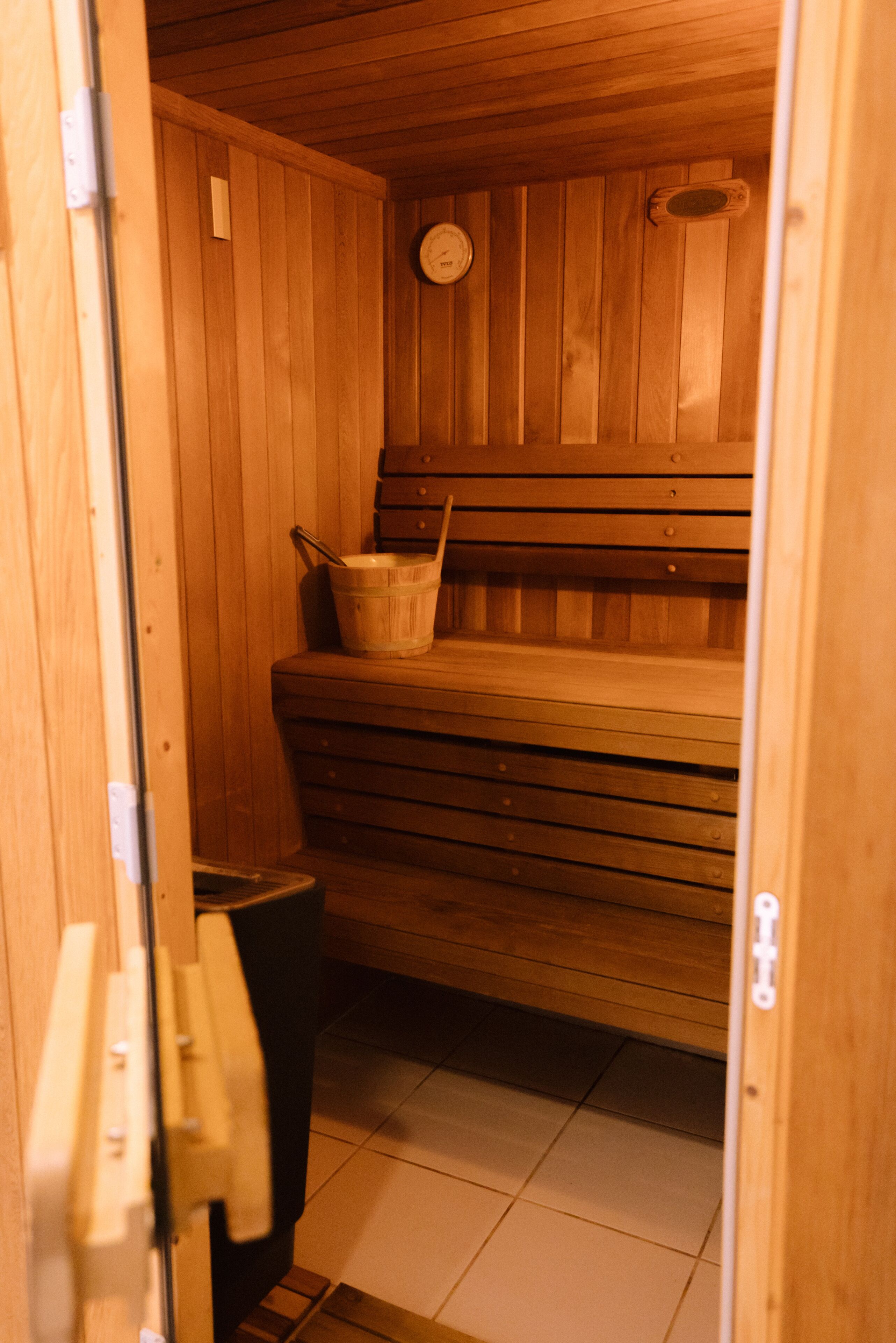 A wooden sauna with a bench and a bucket.