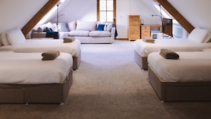 Ein Schlafzimmer im Dachgeschoss mit zwei Betten, einem Schlafsofa, einem Schminktisch und einem Fenster.
