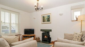 A living room with a fireplace, television, and comfortable seating. - Capella Cottage (Keswick)
