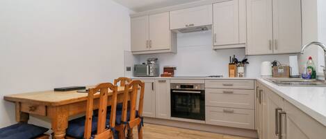 A compact kitchen with a dining table and chairs, a microwave, oven, and a sink.