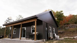 Een modern huis met een overdekte veranda, een barbecue en een groot raam.