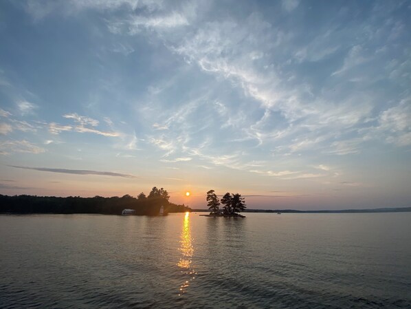 A calm lake at sunset with a small island in the center.