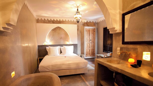 A bedroom with a bed, a bathtub, and a bathroom with a sink and mirror. - Spacious 5-bedroom riad in charming Marrakesh with AC, WiFi and Pool (Marrakesh)