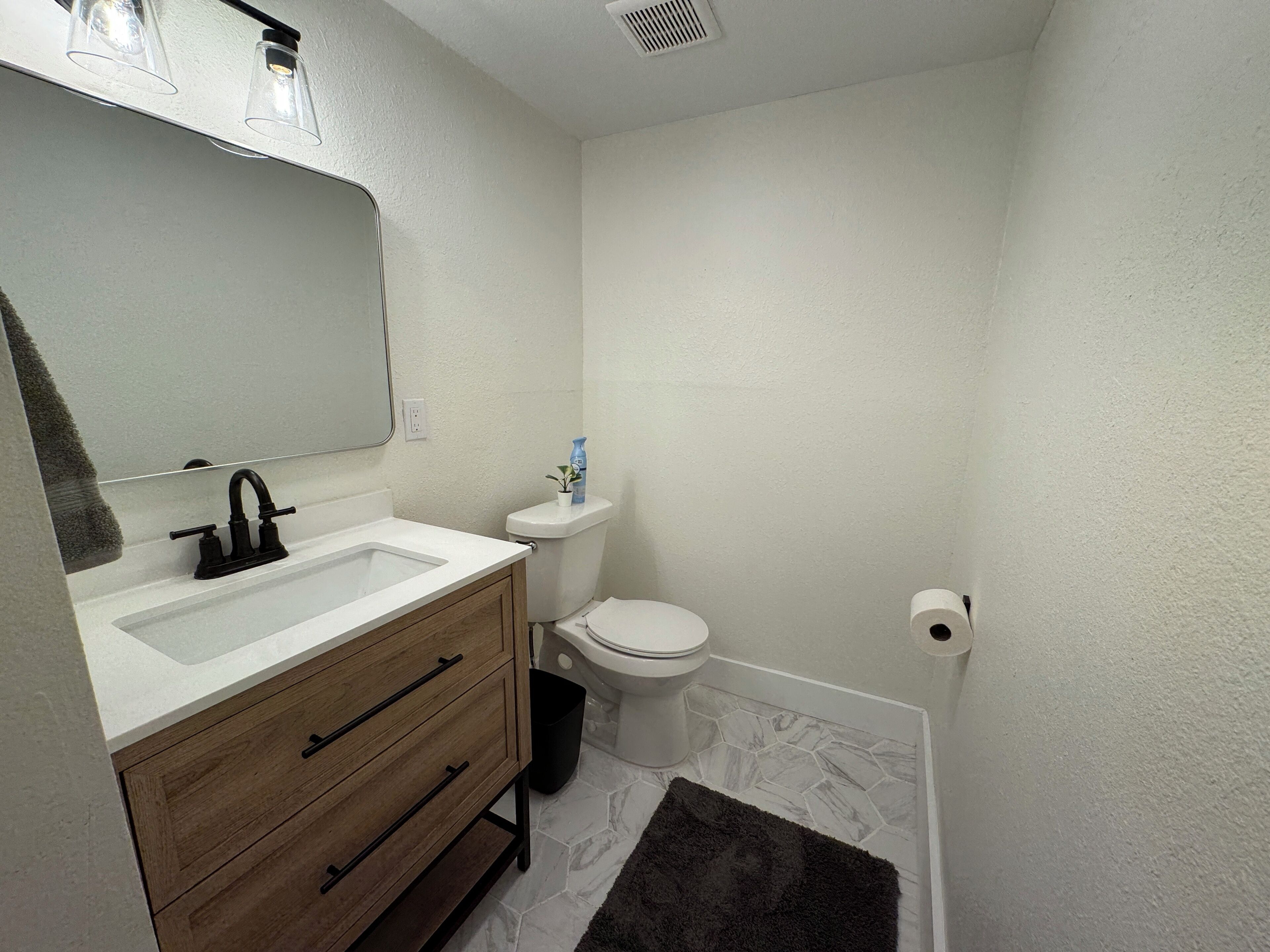 A small bathroom with a white sink, wooden vanity, and a toilet.