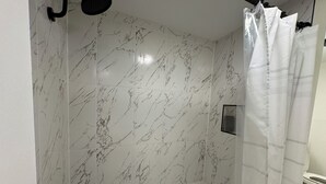 A bathroom with a bathtub, a shower curtain, and marble tiles.