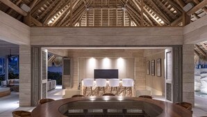 A spacious room with a high ceiling, a central circular table with chairs, and a television on the wall. - Lagos del Mar (Punta de Mita)