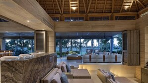 A spacious indoor area with a reception desk, multiple seating areas, and large windows offering views of palm trees. - Lagos del Mar (Punta de Mita)