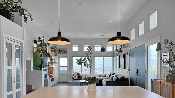 A modern kitchen with a large island, two pendant lights, and a view of the city through large windows. - Mountain Top 4 Bdrm Home Along Nature Reserve with Spectacular Views, AC & WiFi (Spring Valley)