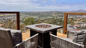 A deck with a stone table and two chairs, overlooking a cityscape. - Mountain Top 4 Bdrm Home Along Nature Reserve with Spectacular Views, AC & WiFi (Spring Valley)