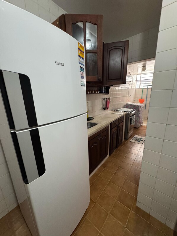 A kitchen with a white refrigerator, wooden cabinets, and a tiled backsplash.