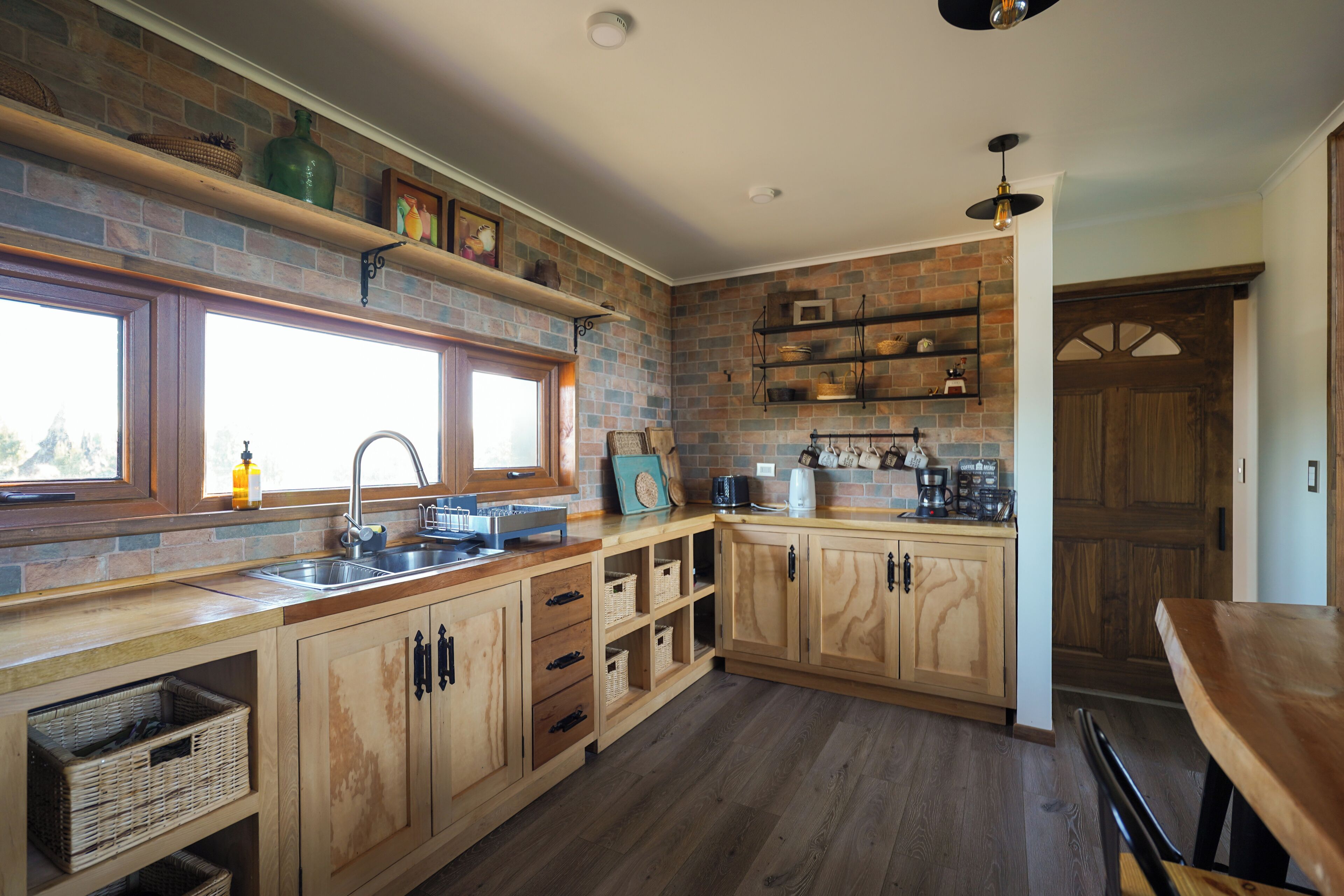 A kitchen with wooden cabinets, a brick backsplash, and a window.