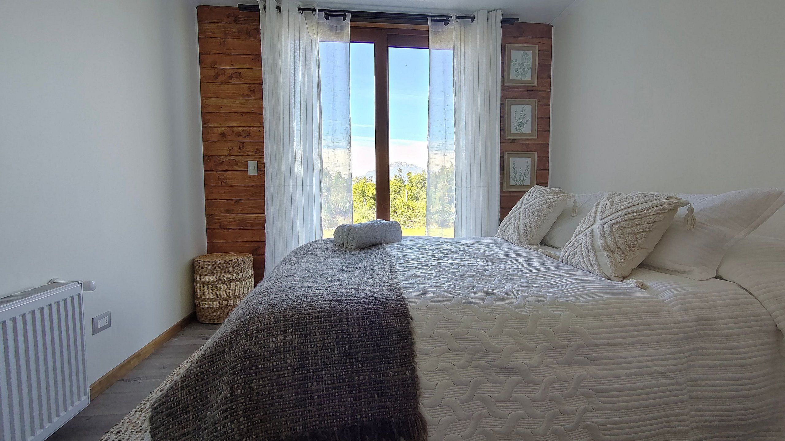 Un dormitorio con una cama, vistas a través de una ventana y una pared de madera.