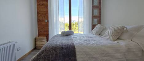 Un dormitorio con una cama, vistas a través de una ventana y una pared de madera.
