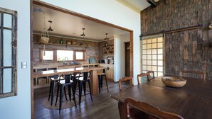 Une cuisine dotée d’un îlot central, de tabourets de bar et d’une table à manger avec des chaises.