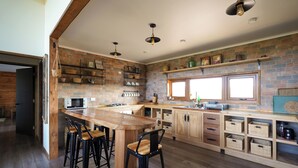 Une cuisine dotée d’un grand îlot central, de tabourets de bar, de meubles en bois et d’un mur en briques.
